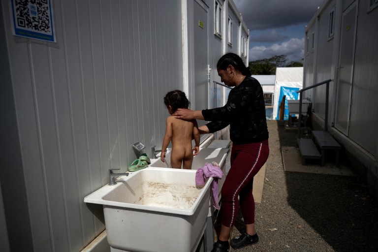 -FOTOGALERÍA- AME4250. BAJO CHIQUITO (PANAMÁ), 21/03/2023.- Una migrante baña a su hijo en la Estación de Recepción Migratoria (ERM) de San Vicente en Metetí (Panamá), el 11 de marzo de 2023. "Guerreros", repiten las madres, hijos guerreros que han aguantado largas caminatas, hambre, sed, el calor, picaduras de insectos, superar ríos y cerros, para sobrevivir a la selva del Darién en su ruta hacia Estados Unidos. Recién salidos de esta selva que hace de frontera natural entre Colombia y Panamá, los migrantes llegan hasta la conocida como Quebrada del León, donde les esperan unas piraguas de indígenas que los descenderán por el casi seco río Tuquesa hasta Bajo Chiquito, una pequeña población emberá donde podrán al fin reposar tranquilos. EFE/ Bienvenido Velasco