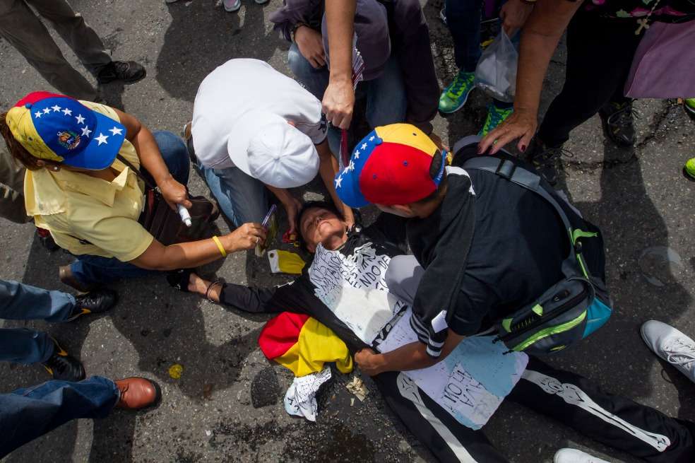 Una mujer recibe atención durante la protesta del miércoles frente a miembros de la Policía Nacional Bolivariana. / EFE