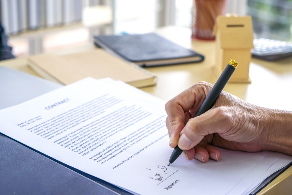 Un señor firma un contrato.