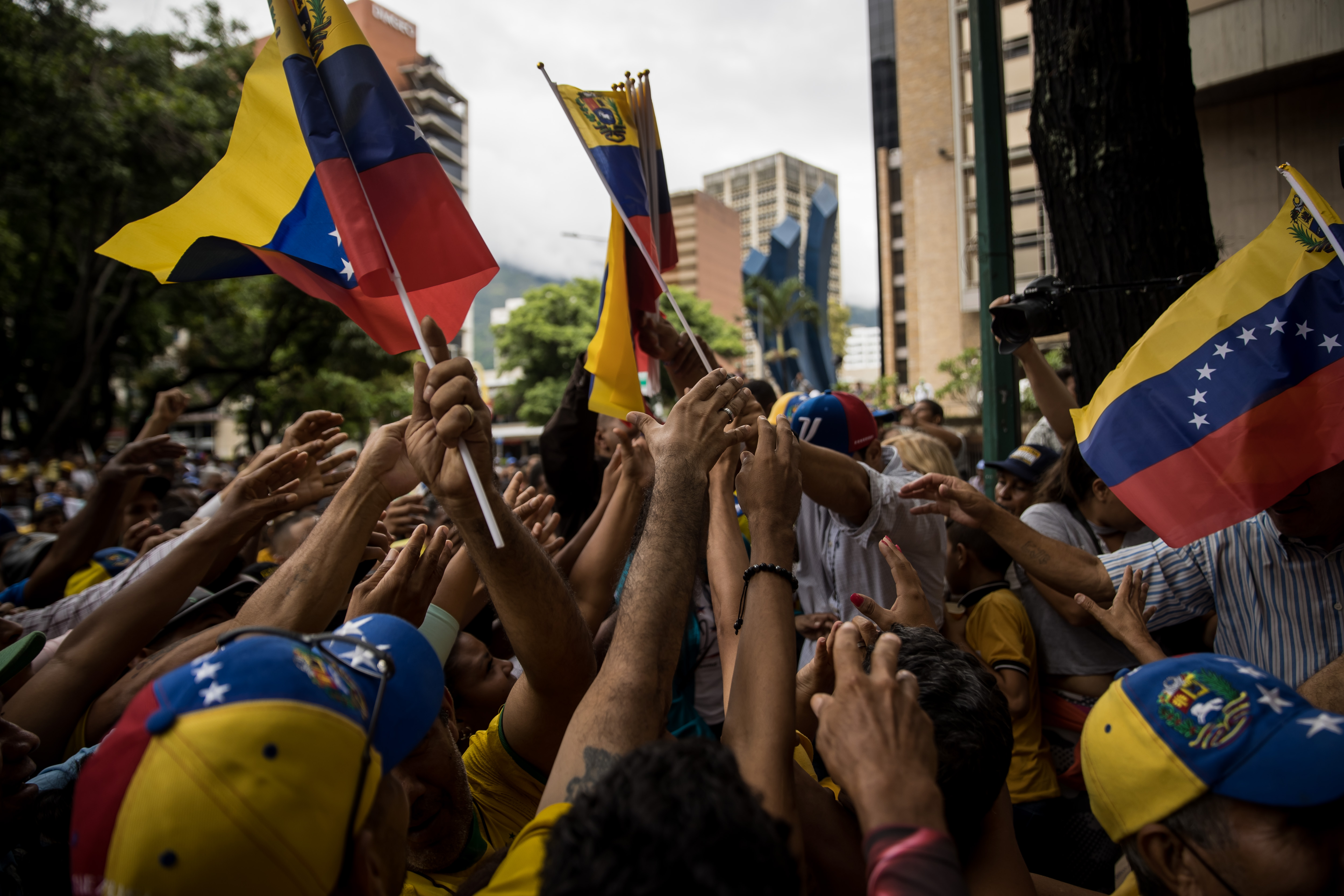 AME2915. CARACAS (VENEZUELA), 14/07/2023.- Fotografía de archivo fechada el 24 de junio del 2023 personas mientras sostienen banderas de Venezuela en un acto político, en Caracas (Venezuela). Las instituciones, el Gobierno, la oposición y el pueblo de Venezuela están calentando el escenario político de cara a las primarias que el antichavismo celebrará el 22 de octubre, un hito hacia el que el país camina entre discursos altisonantes y amenazas que van recrudeciéndose, cuando todavía faltan 100 días para la cita. EFE/ Miguel Gutierrez