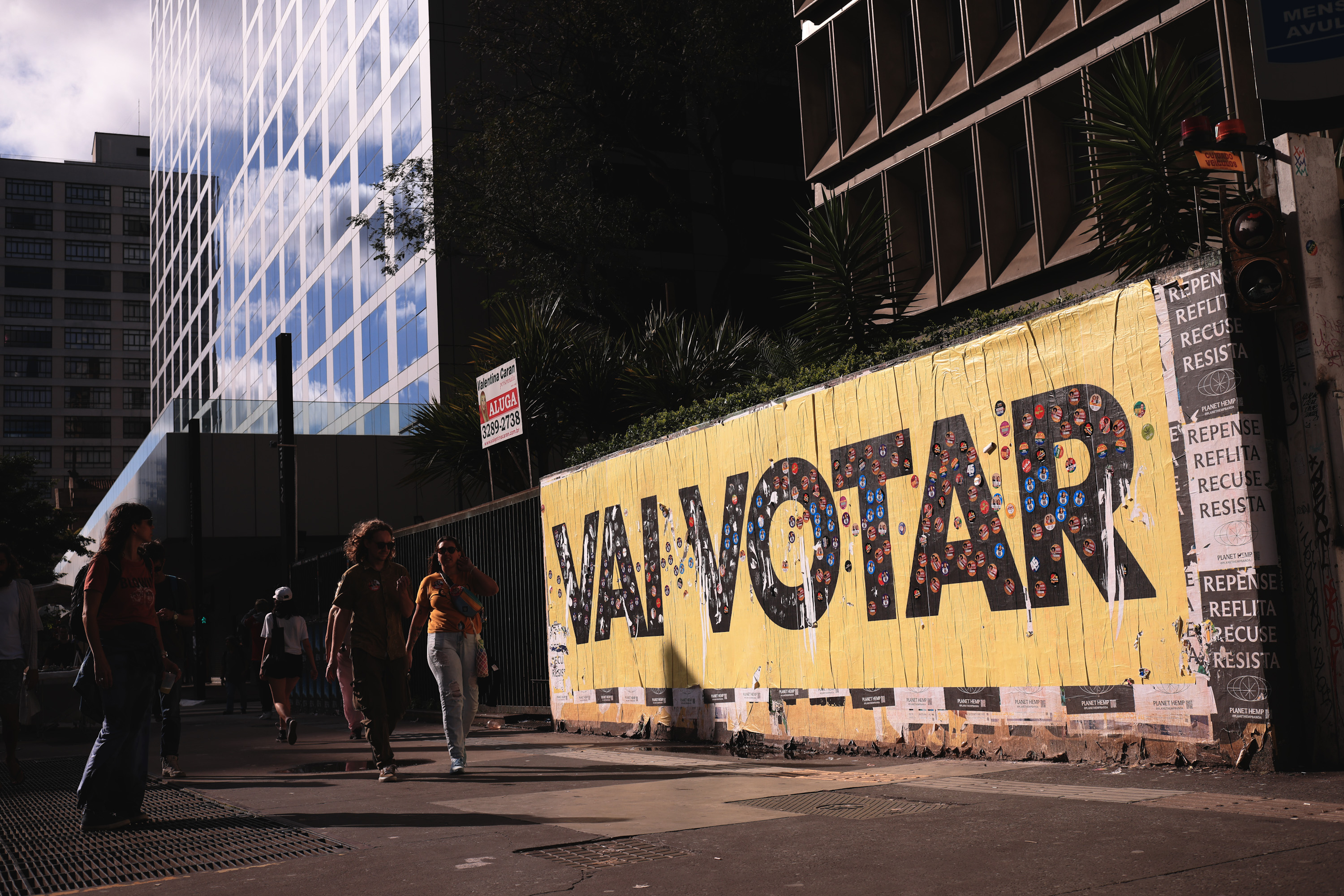 AME1534. SAO PAULO (BRASIL), 02/10/2022.- Varias personas caminan frente a un mural sobre las elecciones, hoy, en Sao Paulo (Brasil). Los comicios presidenciales, legislativos y regionales en Brasil transcurren este domingo con normalidad en sus primeras horas, con pocos casos registrados de problemas en las urnas electrónicas y de delitos electorales, comunicaron las autoridades. Las elecciones de 2022, las más polarizadas desde que Brasil recuperó la democracia en 1985, se han caracterizado por un clima de crispación entre el exmandatario Luiz Inácio Lula da Silva, el gran favorito en las encuestas de intención de voto, y el actual presidente, Jair Bolsonaro, quien busca la reelección. EFE/ Ettore Chiereguini