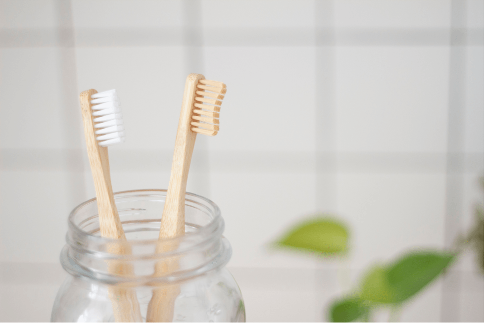 Dos cepillos de dientes de bambú en un vaso