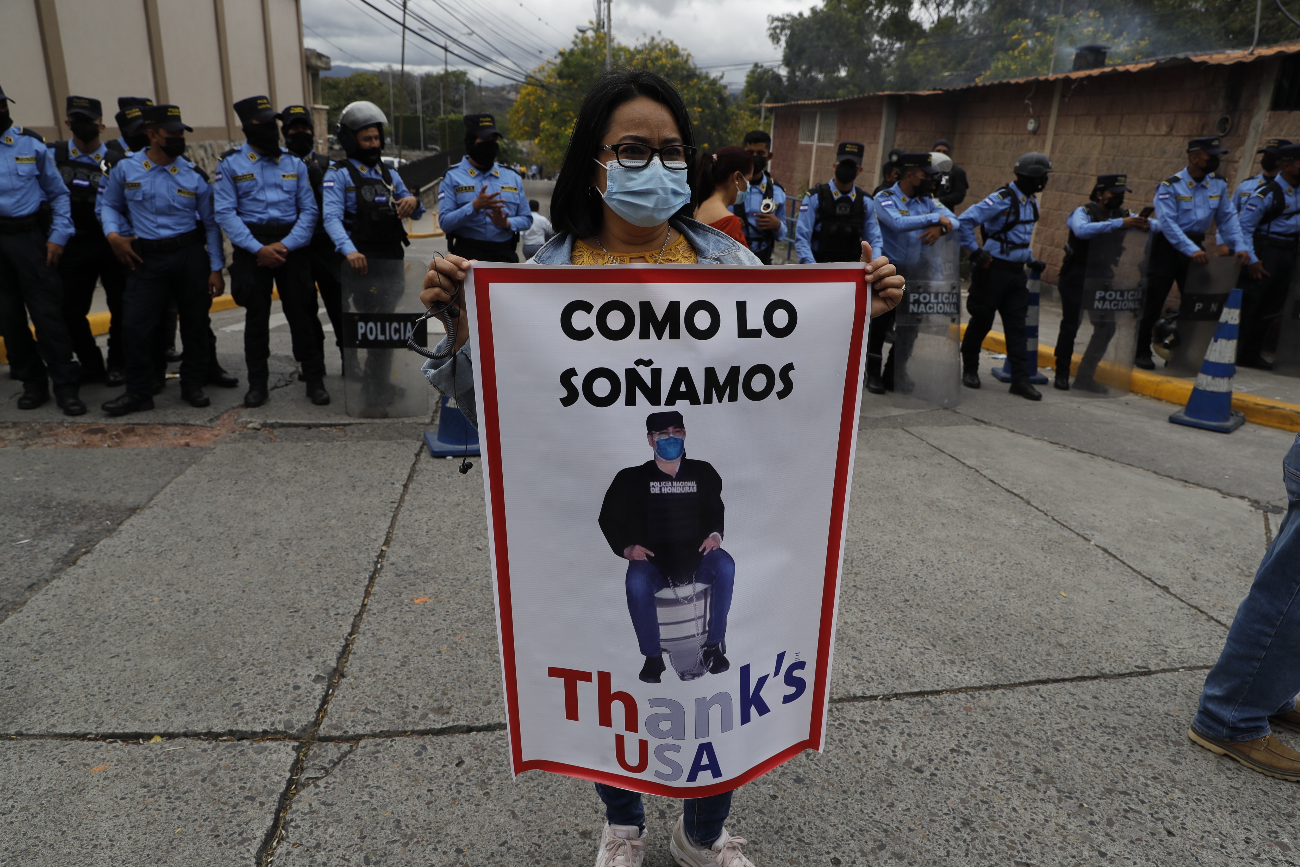 AME6198. TEGUCIGALPA (HONDURAS), 16/02/2022.- Una persona simpatizante del Partido Libertad y Refundación (LIBRE), de la actual presidenta Xiomara Castro y su esposo Manuel Zelaya, muestra un cartel contra el expresidente de Honduras, Juan Orlando Hernández, quien comparece hoy ante un juez, en los alrededores de la Corte Suprema de Justicia, en Tegucigalpa (Honduras). Hernández fue capturado en su casa en Tegucigalpa, la capital hondureña, luego de que el juez ordenó su captura al conocer la petición de detención con fines de extradición hecha por Estados Unidos. EFE/ Gustavo Amador