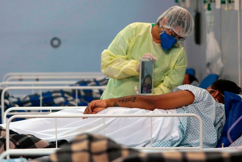Una enfermera en Brasil ayuda a un paciente con coronavirus a hablar con su familia por una videollamada. / AFP