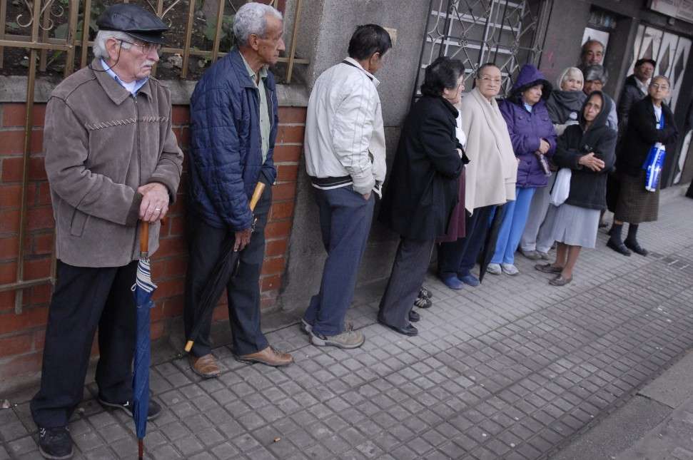 Varios pensionados hacen fila en la calle.