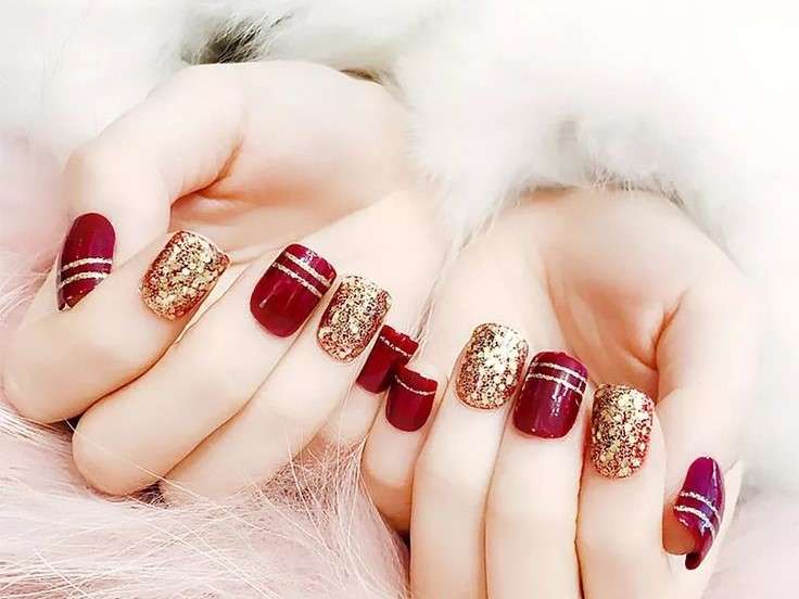 Para este diseño, necesitarás esmalte de uñas rojo y dorado, así como cinta adhesiva para uñas. Pinta tus uñas de rojo y deja que se sequen. Luego, coloca la cinta adhesiva en tus uñas en el patrón que prefieras y pinta encima con el esmalte dorado. Retira la cinta adhesiva antes de que el esmalte dorado se seque.