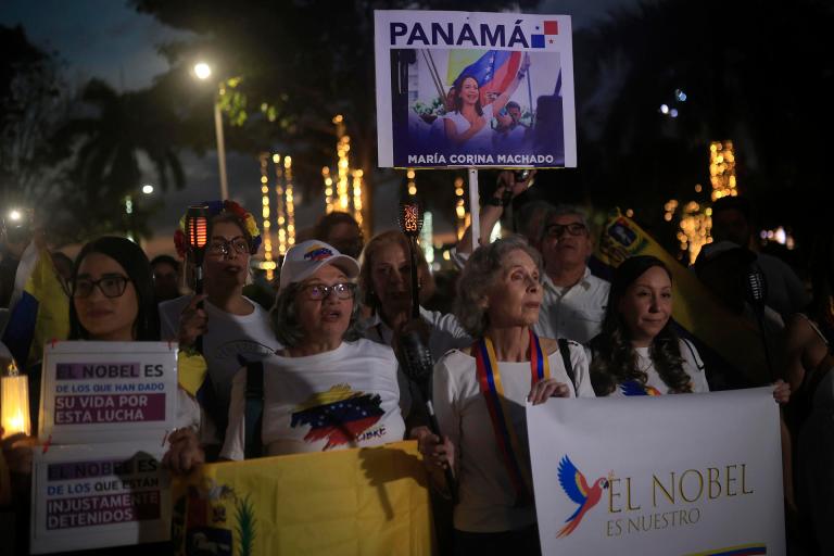 AME6424. CIUDAD DE PANAMÁ (PANAMÁ), 06/12/2025.- Personas sostienen carteles durante la marcha "por la paz y la libertad" en Venezuela este sábado, en Ciudad de Panamá (Panamá). Decenas de venezolanos se sumaron en Panamá a las marchas globales "por la paz y la libertad" en Venezuela convocadas el jueves por la líder opositora y exdiputada del país sudamericano María Corina Machado. EFE/ Bienvenido Velasco