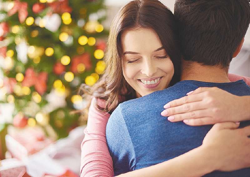 Smiling woman embracing her boyfriend in Christmas