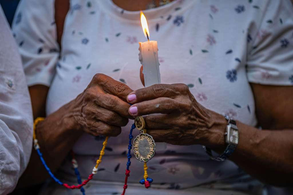 AME9122. CARACAS (VENEZUELA), 08/08/2024.- Una mujer sostiene una vela durante la gran vigilia nacional por los presos políticos convocada por la oposición, este jueves en la plaza Los Palos Grandes, en Caracas (Venezuela). EFE/ Henry Chirinos