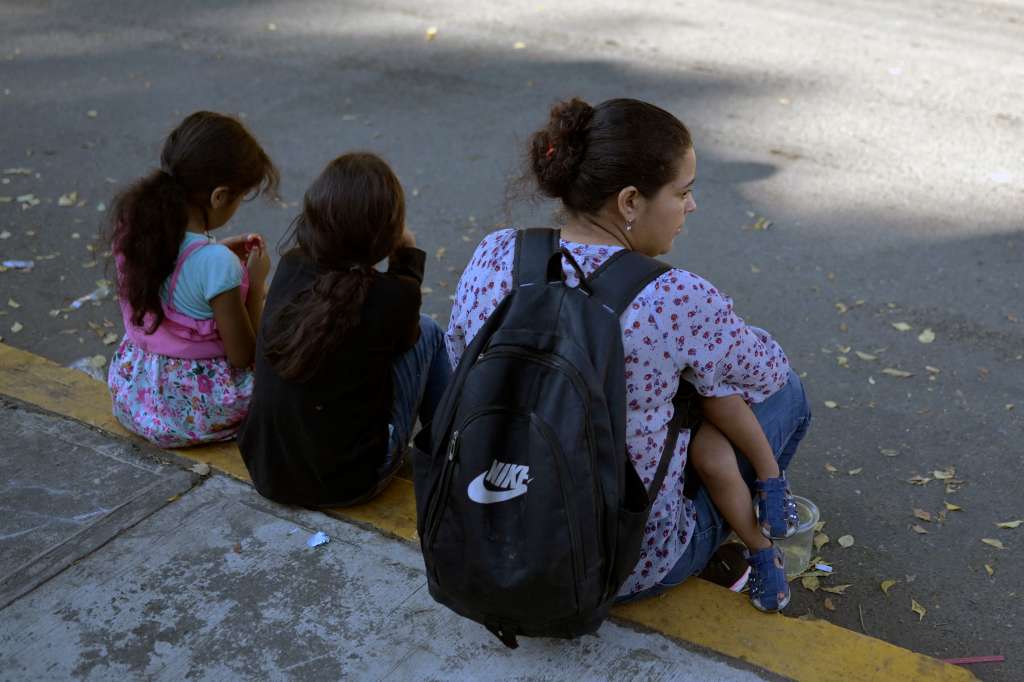 A woman migrant with three children waits outside the regional office of the National Migration Institute to await their safe conduct to transit through Mexican territory on their way to the United States, in Tapachula, Chiapas state, Mexico on January 13, 2025.