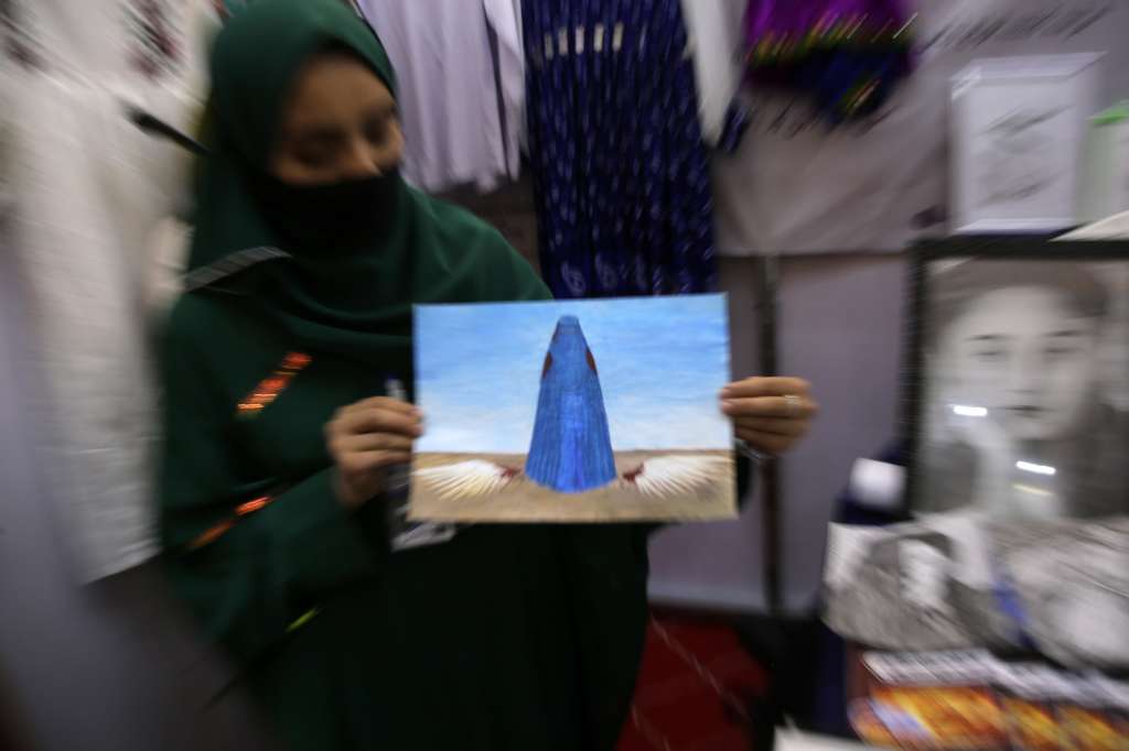 Kabul (Afghanistan), 27/08/2024.- An Afghan woman shows a painting at a stand of the 'Afghanistan's Economic Development and Success' in Kabul, Afghanistan, 27 August 2024. A four-day exhibition titled 'Afghanistan's Economic Development and Success' has opened in Kabul, showcasing products from industrialists in 310 booths, with 150 dedicated to handicrafts. The Taliban Ministry of Industry and Trade said it emphasizes the importance of such exhibitions for promoting domestic products to enhance economic growth. The Chamber of Commerce and Investment reports a significant increase in exports and a decrease in imports, highlighting the role of the private sector in this progress. Additionally, the Chamber of Agriculture and Livestock stresses the need to support agriculture for overall economic development. (Afganistán) EFE/EPA/SAMIULLAH POPAL