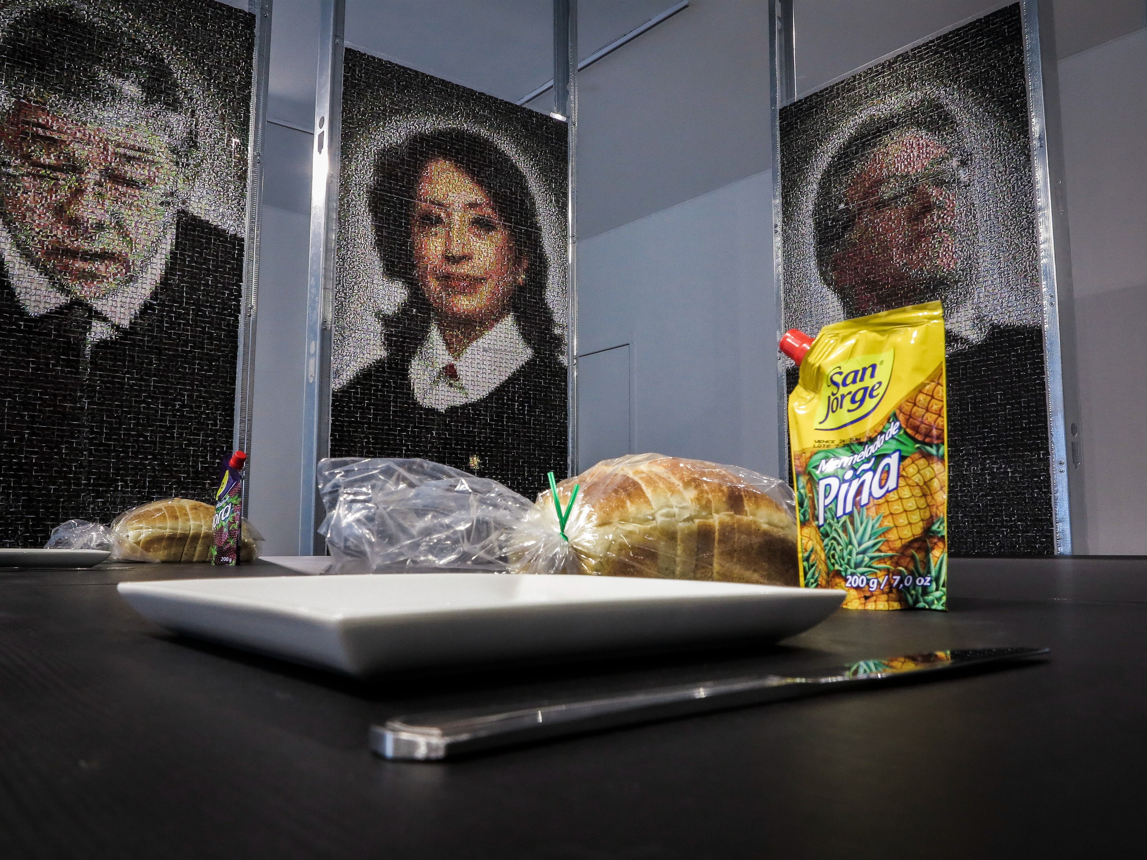 En la instalación 'Mermelada' del artista colombiano Paolo Almario, ganador del Premio 'Start of the ART(ist)" 2026 de Ars Electronica, máquinas robóticas destruyen lentamente retratos en mosaico "creados a partir de miles de etiquetas de mermelada" de los magistrados, fiscales y el jefe de Estado responsables del caso fabricado contra el padre del artista en Colombia, mientras los visitantes comen pan y mermelada colombiana.