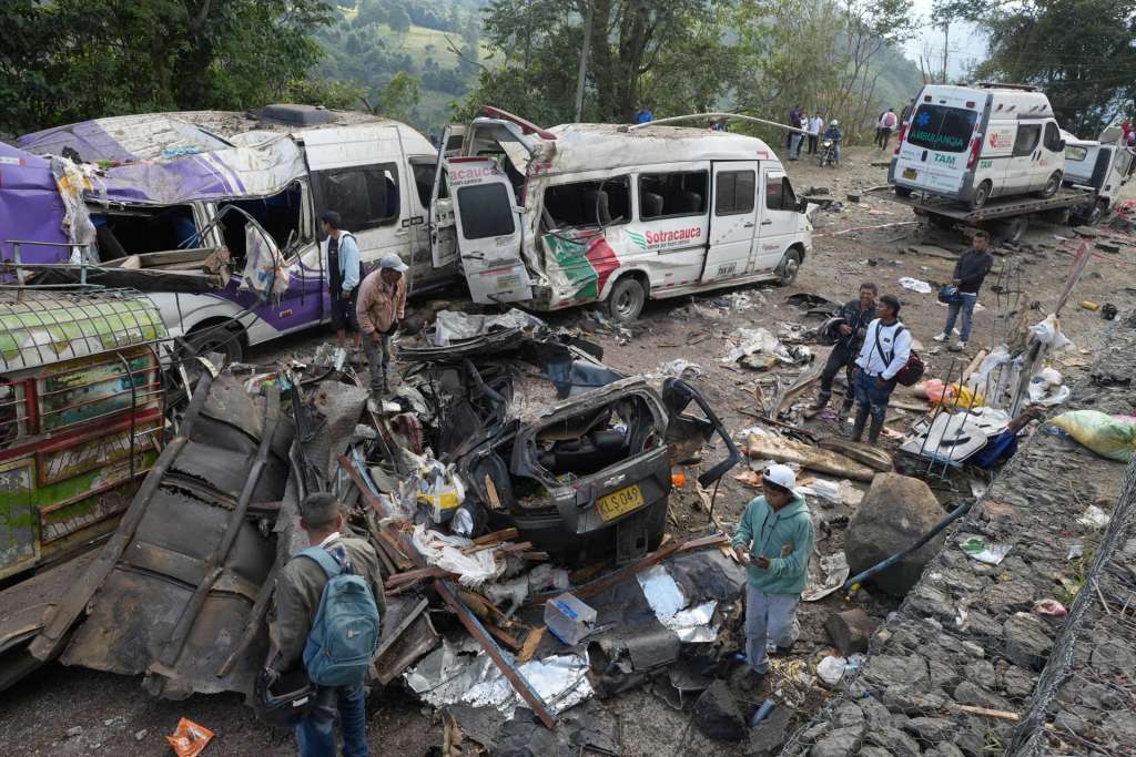 AME6839. CAJIBÍO (COLOMBIA), 26/04/2026.- Personas observan este domingo vehículos destruidos por un atentado ocurrido en la Vía Panamericana en Cajibío (Colombia). El número de personas muertas por el ataque guerrillero de este sábado con un cilindro bomba en la Vía Panamericana, en el suroeste de Colombia, subió a 14, todos civiles, y el de heridos a 38, informó el gobernador del departamento del Cauca, Octavio Guzmán. EFE/Ernesto Guzmán