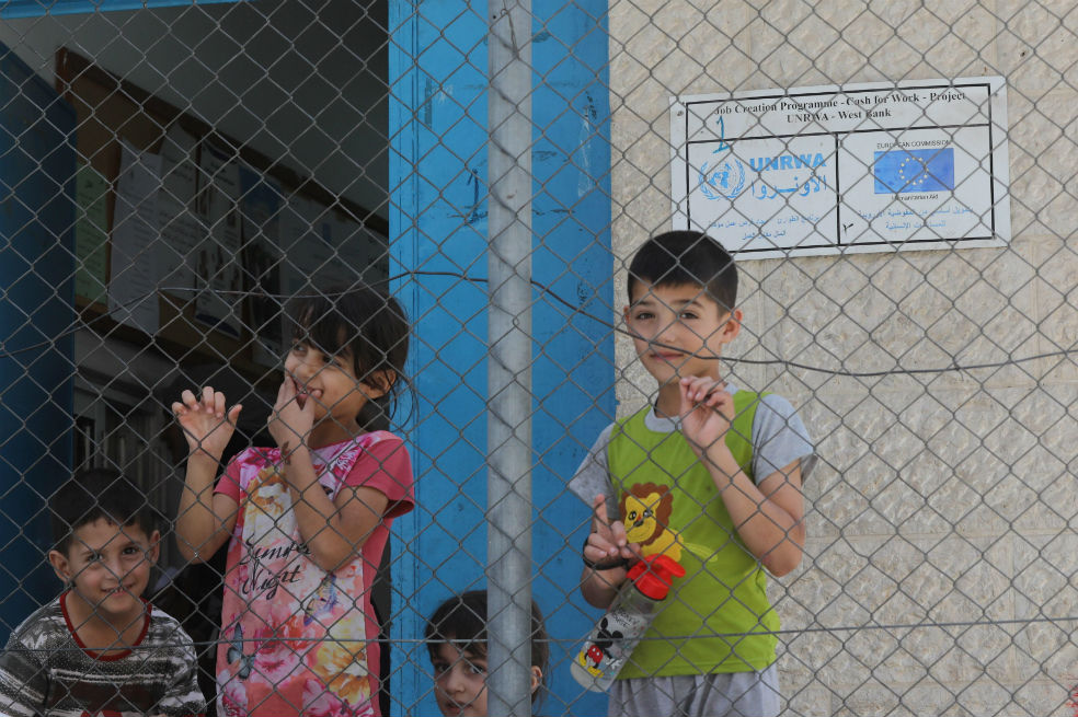 Varios niños aguardan a las puertas de un centro de salud en el campo de refugiados de Al Ein cerca de la ciudad cisjordana de Nablus. / EFE