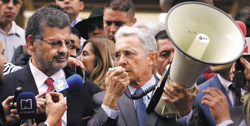 El expresidente y actual senador por el Centro Democrático, Álvaro Uribe (d), sostiene un megáfono mientras habla con los medios de comunicación acompañado por el abogado Jaime Granados (i) hoy, viernes 23 de febrero de 2018, a su llegada a la Corte Suprema de Justicia en Bogotá (Colombia), para atender un requerimiento por una investigación de manipulación de testigos