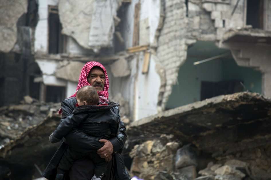 Un hombre con un niño evacúa hacia la zona de Alepo en control del gobierno tras cuatro semanas de intensos bombardeos. / AFP