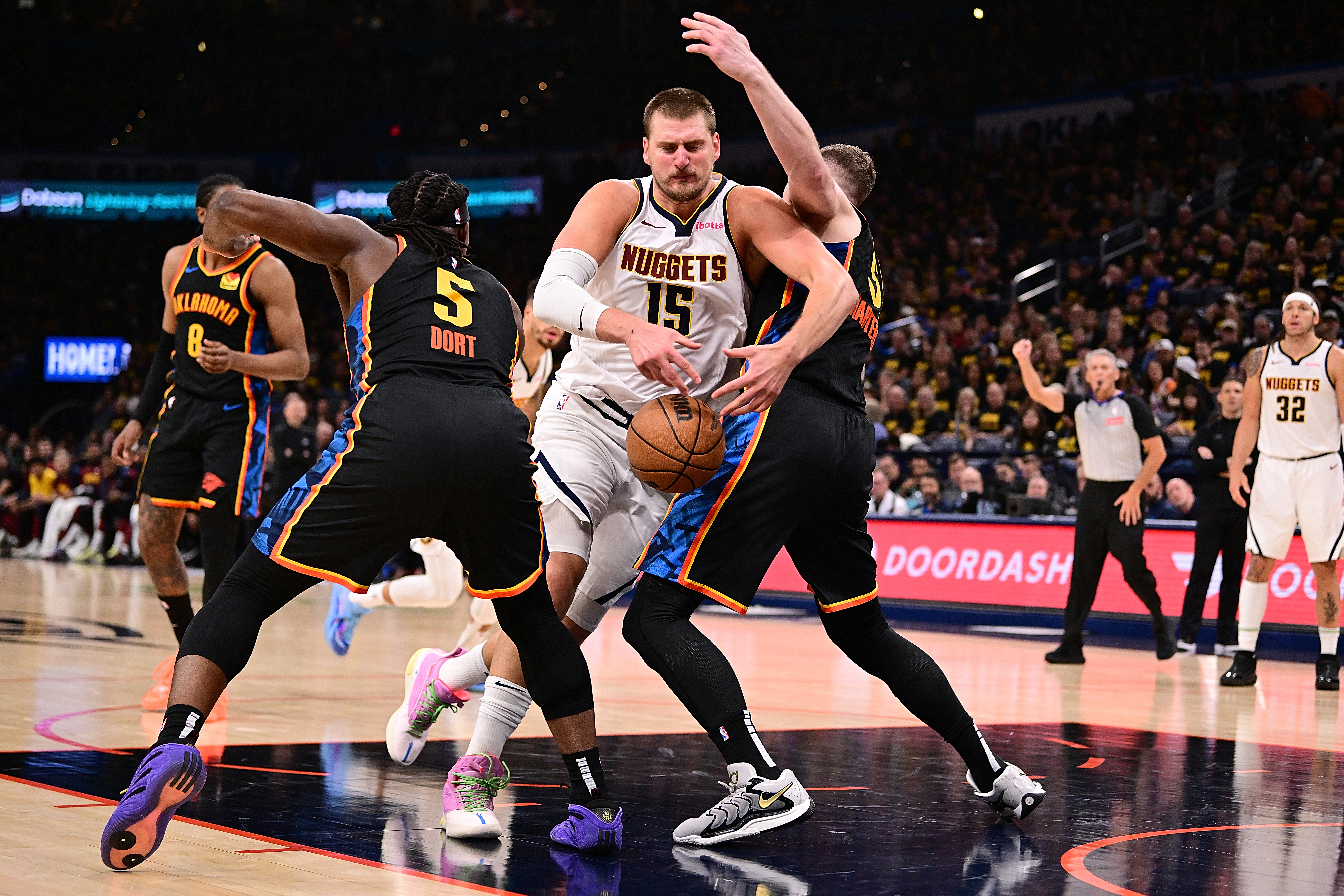 Nikola Jokic intenta pasar a Isaiah Hartenstein y Luguentz Dort.
