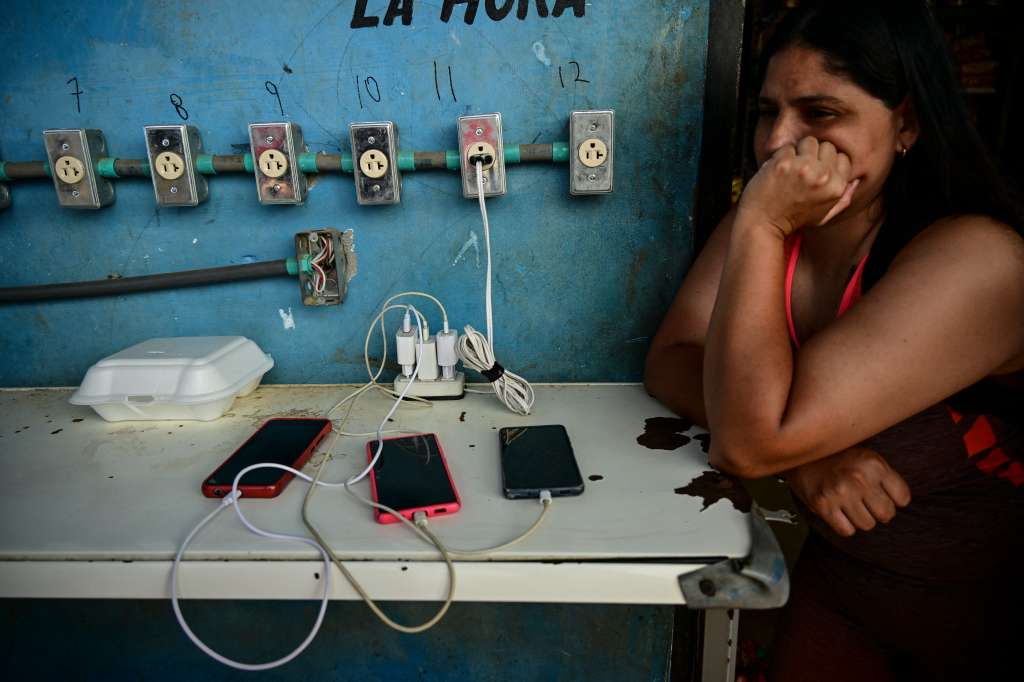 A migrant charges her phone while waiting for a bus to take her to the Costa Rica border in the Reception Center for Migrant Care in Lajas Blancas, in the jungle province of Darien, Panama on June 27, 2024.