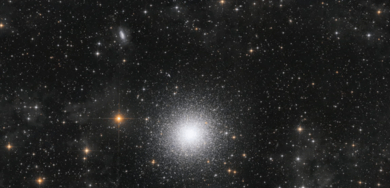 "Es el increíble equilibrio de detalles a diferentes distancias lo que hace que esta imagen sea realmente impresionante. Sutil nubes grises de polvo interestelar y un campo de estrellas locales componen el primer plano. En la distancia media se encuentra el Gran Cúmulo de Hércules, capturado maravillosamente hasta su núcleo luminoso. Pero es el fondo lo que completa esta imagen. Docenas de galaxias salpican la escena. Cuanto más se mira, más se revelan, hasta el punto de que empieza a hacerle sombra al Campo Profundo del Hubble. Con un enfoque nítido y hermosas explosiones de color, es una digna ganadora de la categoría".