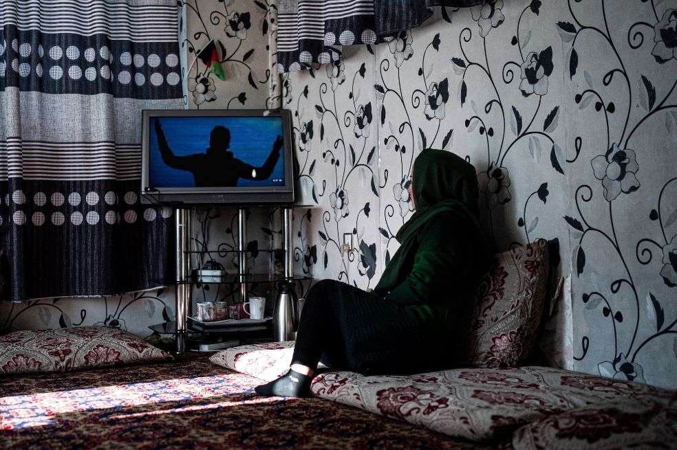Una sobreviviente de violencia de género mira televisión en un refugio para mujeres y niñas afganas en Kabul.