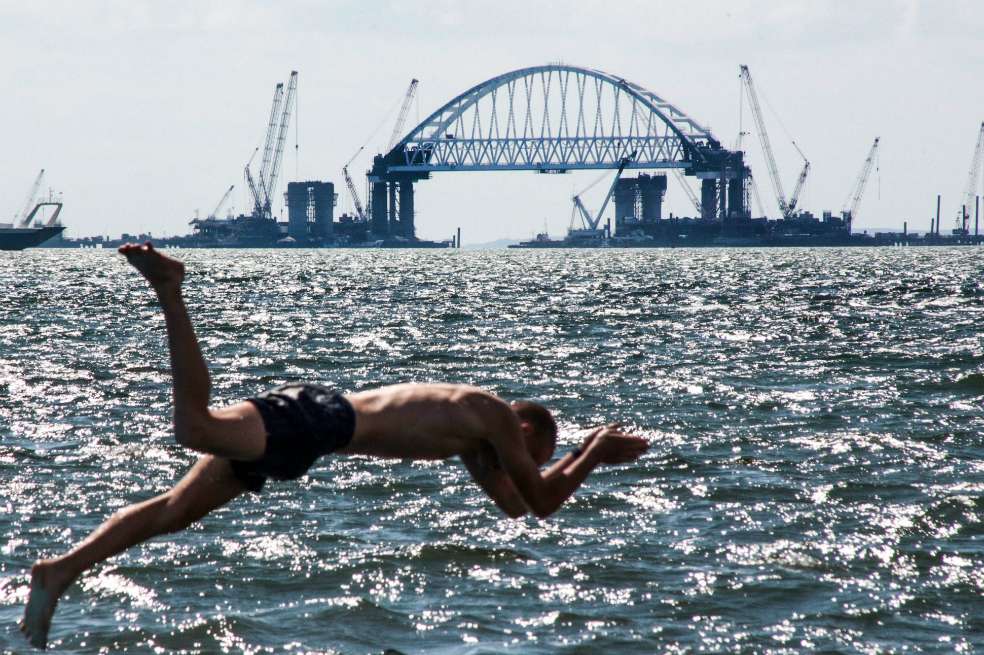 Un hombre salta al agua en el puente del Estrecho de Kerch que conecta el sur de Rusia con Crimea en el Mar de Azov. Este punto es de vital importancia para los intereses comerciales y de seguridad de Rusia y Ucrania. / AFP