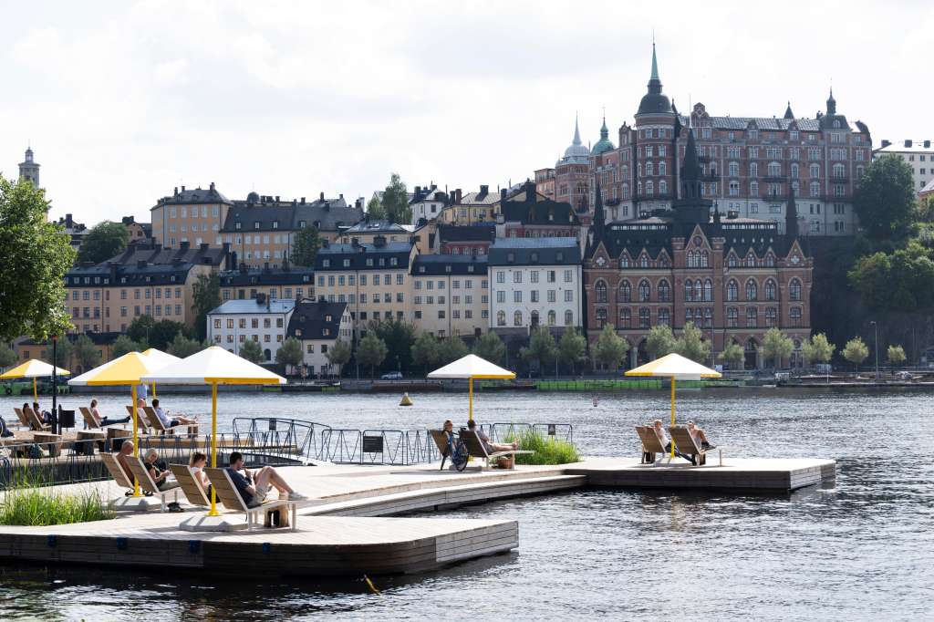 Stockholm (Sweden), 05/08/2024.- People enjoy the warm and summer weather under parasols at the latest addition of viewpoints along the capital's quays, in Stockholm, Sweden, 05 August 2024. The so-called 'Kajbalkongen' is located at Riddarholmen with a view of Lake Malaren and Sodermalm district. (Suecia, Estocolmo) EFE/EPA/FREDERIK SANDBERG SWEDEN OUT