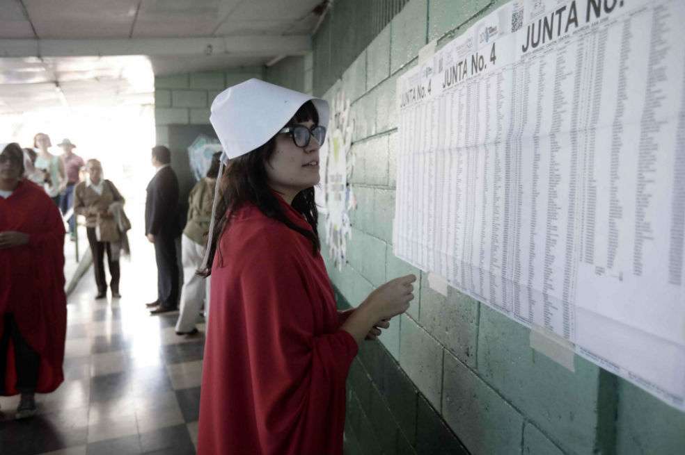 Una mujer del colectivo feminista “Somos Nuestras”, vestida con los trajes de la novela “The Handmade´s Tales”, busca su mesa de votación para las jornadas electorales de este domingo en Costa Rica por las que se escogerá al nuevo presidente. / EFE