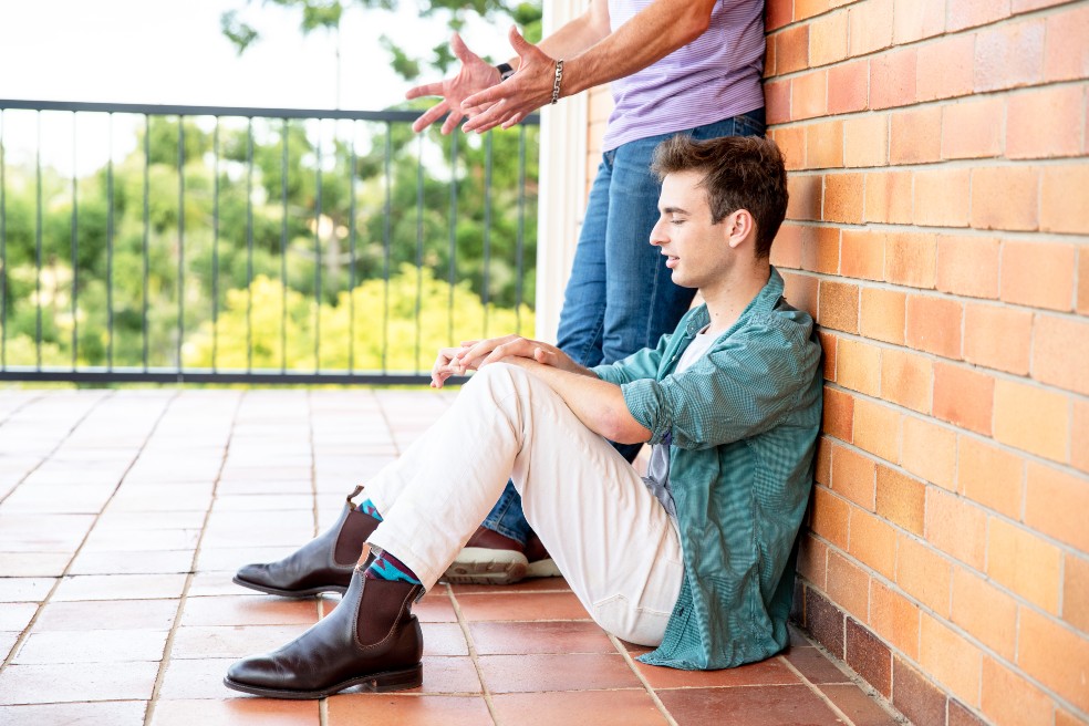 un joven sentado en el suelo escucha a un hombre que padre ser su padre.