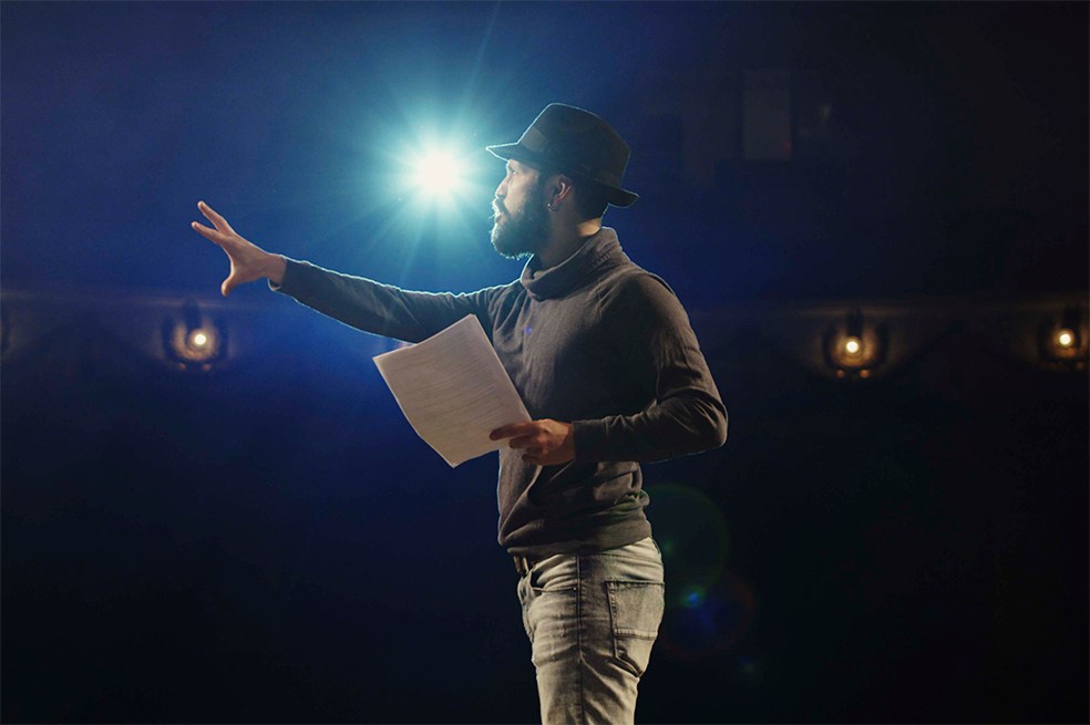 Medium shot of an actor performing a monologue in a theater while holding his script