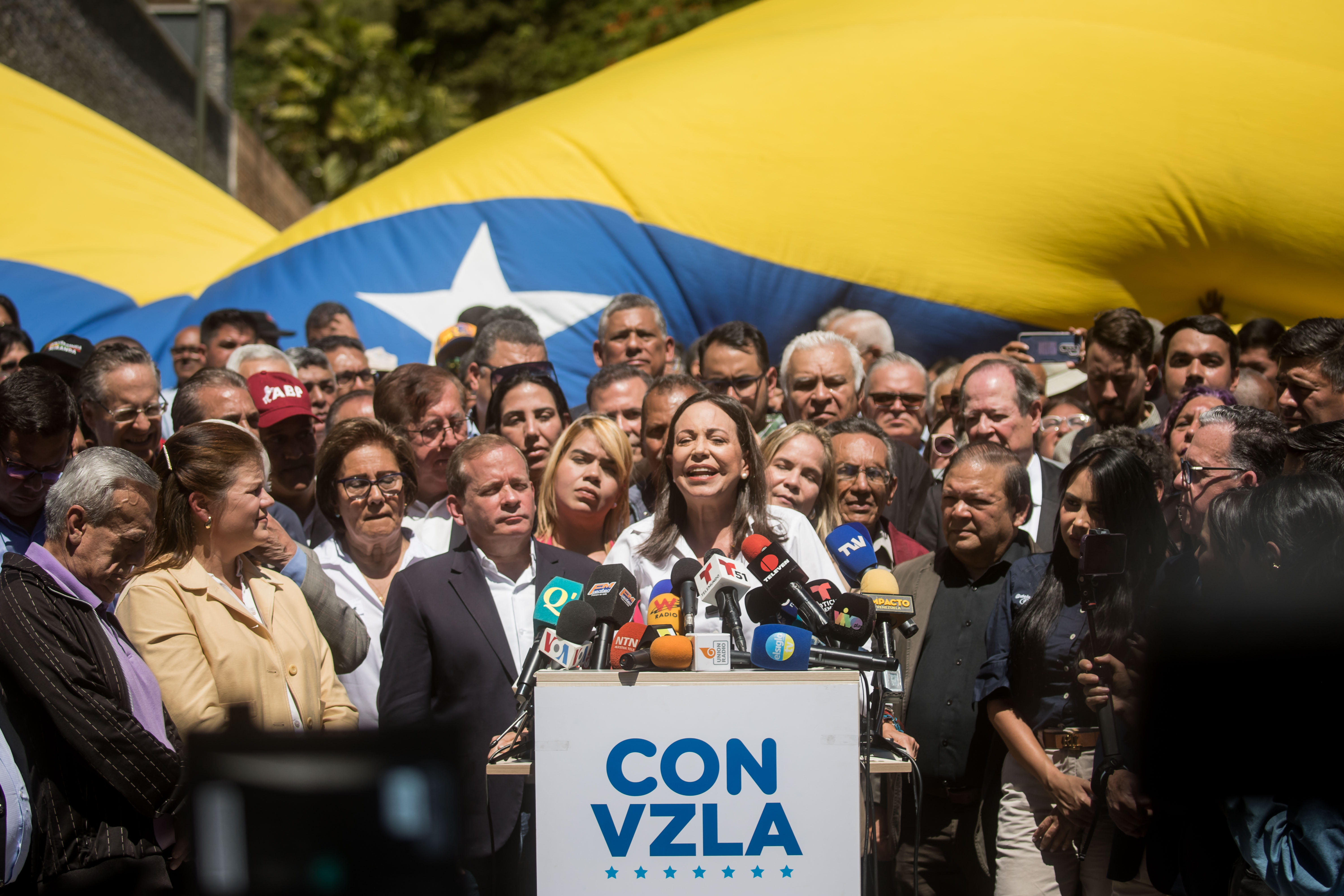 AME3081. CARACAS (VENEZUELA), 29/01/2024.- La líder opositora venezolana María Corina Machado (c) ofrece hoy declaraciones a la prensa durante un acto de calle, en Caracas (Venezuela). Machado aseguró este lunes que competirá en las presidenciales de este año, como candidata del mayor bloque antichavista, pese a la sentencia publicada el viernes en la que el Tribunal Supremo de Jsuticia (TSJ) ratificó que está impedida para participar en comicios hasta 2036. EFE/ MIGUEL GUTIERREZ
