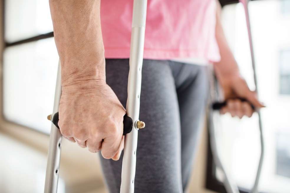 Una mujer camina apoyada en muletas.