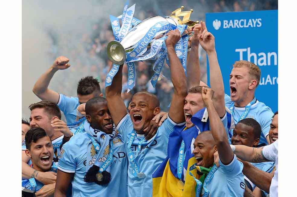El capitán Vincent Kompany levanta la copa que acredita al Manchester City como campeón de la liga inglesa. / AFP