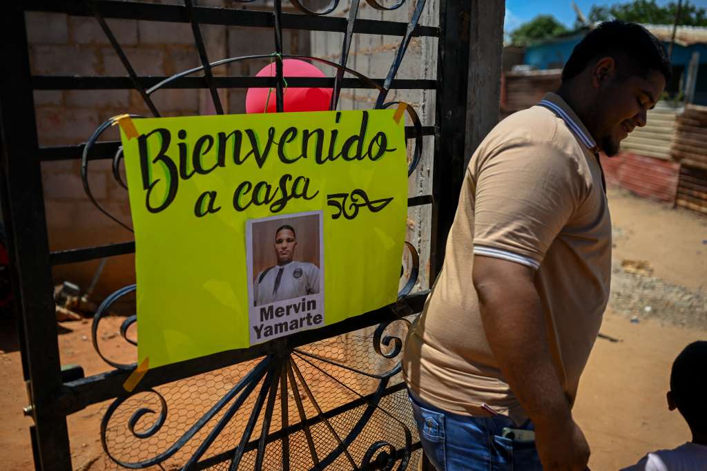En Maracaibo, Jonaiker Alexander Molero espera junto a un cartel de bienvenida a su cuñado, Mervin Yamarte, quien fue repatriado de una cárcel en El Salvador.