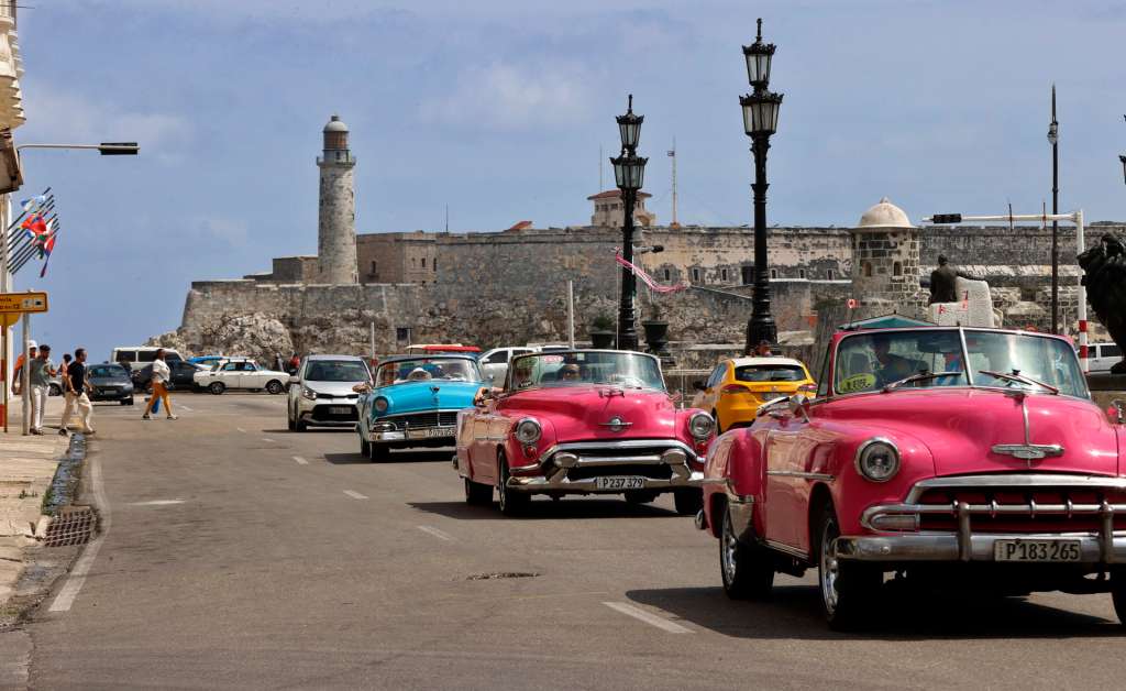 AME2881. LA HABANA (CUBA), 27/04/2025.- Turistas pasean en un auto clásico frente al Castillo del Morro este viernes, en una calle de La Habana (Cuba). El fin de la temporada alta en Cuba ha puesto de nuevo en evidencia que el turismo sigue sin levantar cabeza en una isla que durante décadas tuvo a este sector como motor de la economía y fuente fundamental de divisas. EFE/ Ernesto Mastrascusa