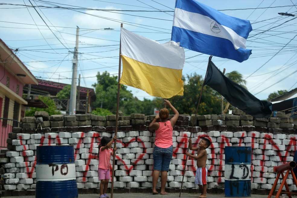 Un mujer con sus hijos ondenado la bandera de Nicaragua y la de Ciudad del Vaticano. / AFP