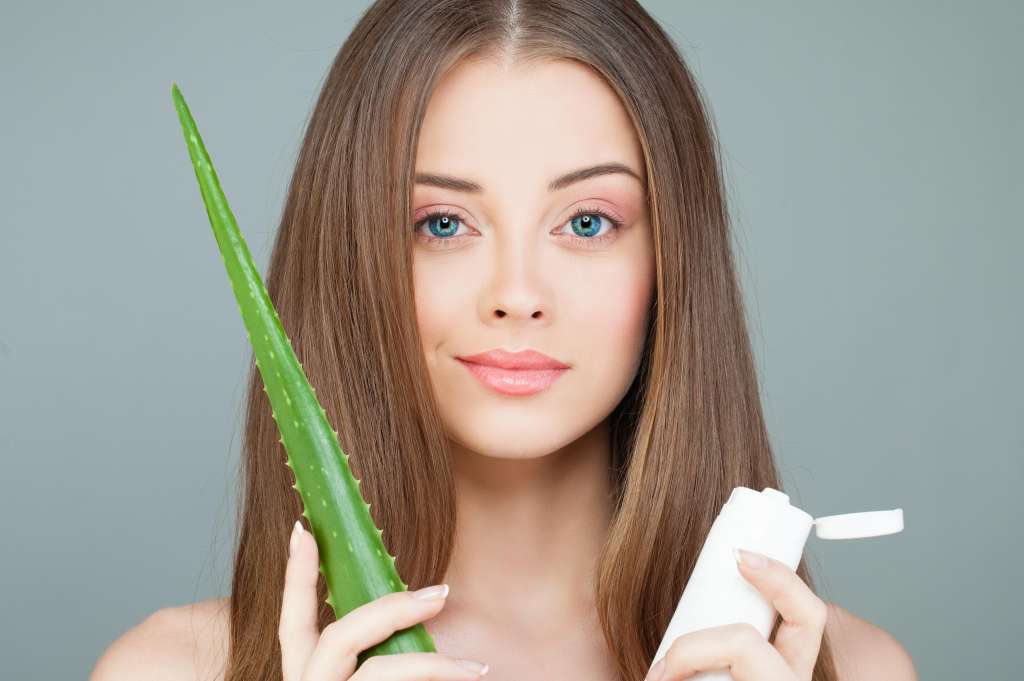 Beautiful Spa Model Woman with Healthy Skin, Green Aloe Leaf, Long Hair and Moisturizer Tube