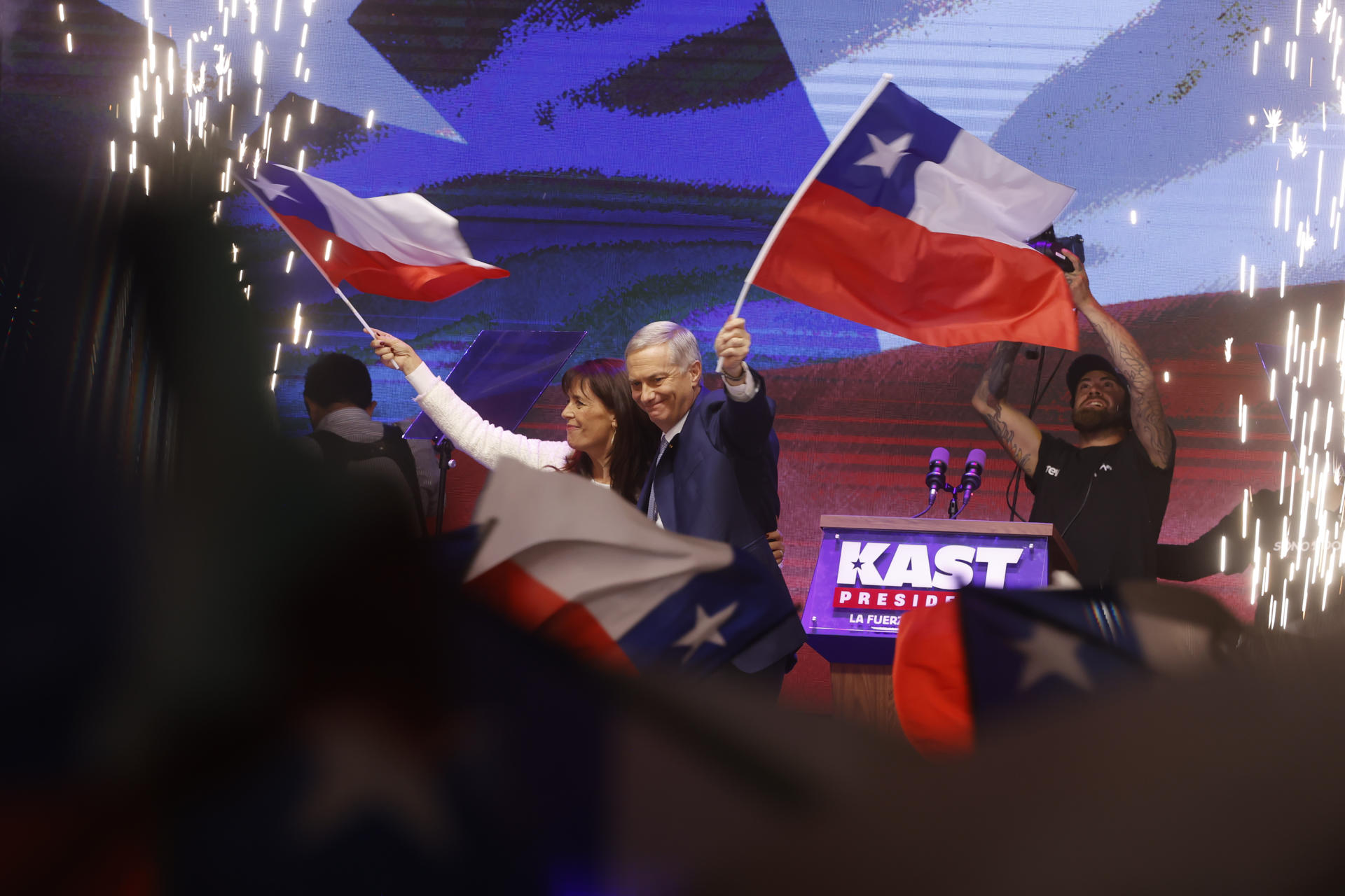 AME8380. SANTIAGO (CHILE), 14/12/2025.- El presidente electo de Chile, el ultraderechista José Antonio Kast, y su esposa, María Pía Adriasola, agitan banderas de Chile este domingo, en Santiago (Chile). Kast dijo que sus prioridades van a ser "seguridad, inmigración y progreso económico" y aseguró que "Chile necesita orden en las calles y en el Estado". EFE/ Elvis González