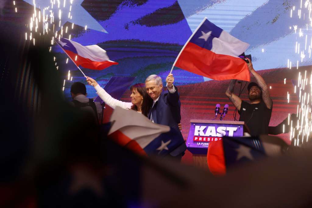 AME8380. SANTIAGO (CHILE), 14/12/2025.- El presidente electo de Chile, el ultraderechista José Antonio Kast, y su esposa, María Pía Adriasola, agitan banderas de Chile este domingo, en Santiago (Chile). Kast dijo que sus prioridades van a ser "seguridad, inmigración y progreso económico" y aseguró que "Chile necesita orden en las calles y en el Estado". EFE/ Elvis González
