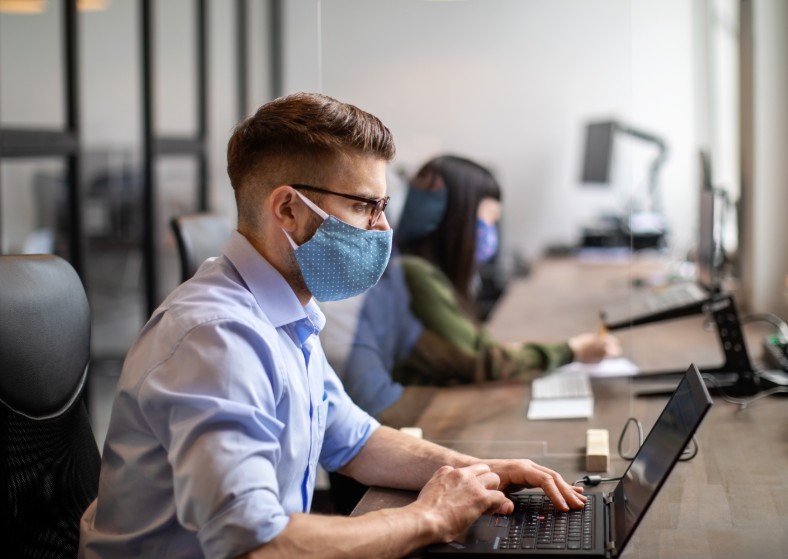 Dos empleados en una oficina grande, trabajn en sus computadores.