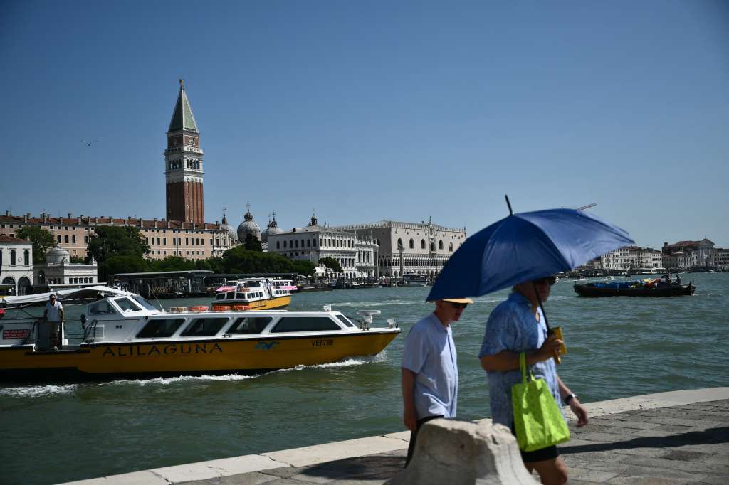 A man protects himelf from the sun with an umbrella, on a hot summer day in Venice on June 28, 2025.