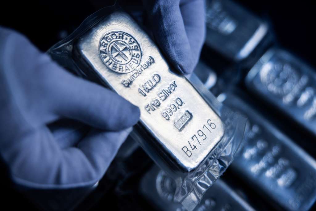 Mano sostiene una pieza de barra de plata.