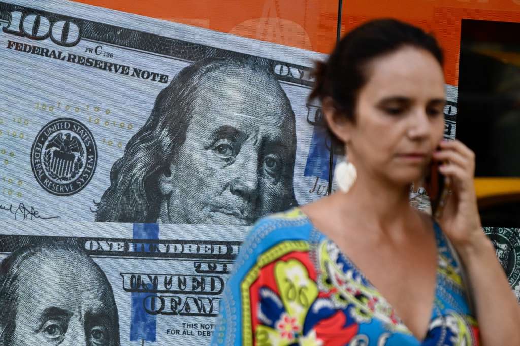 (FILES) A woman walks past an image of one hundred US dollar notes in Buenos Aires on December 12, 2023.