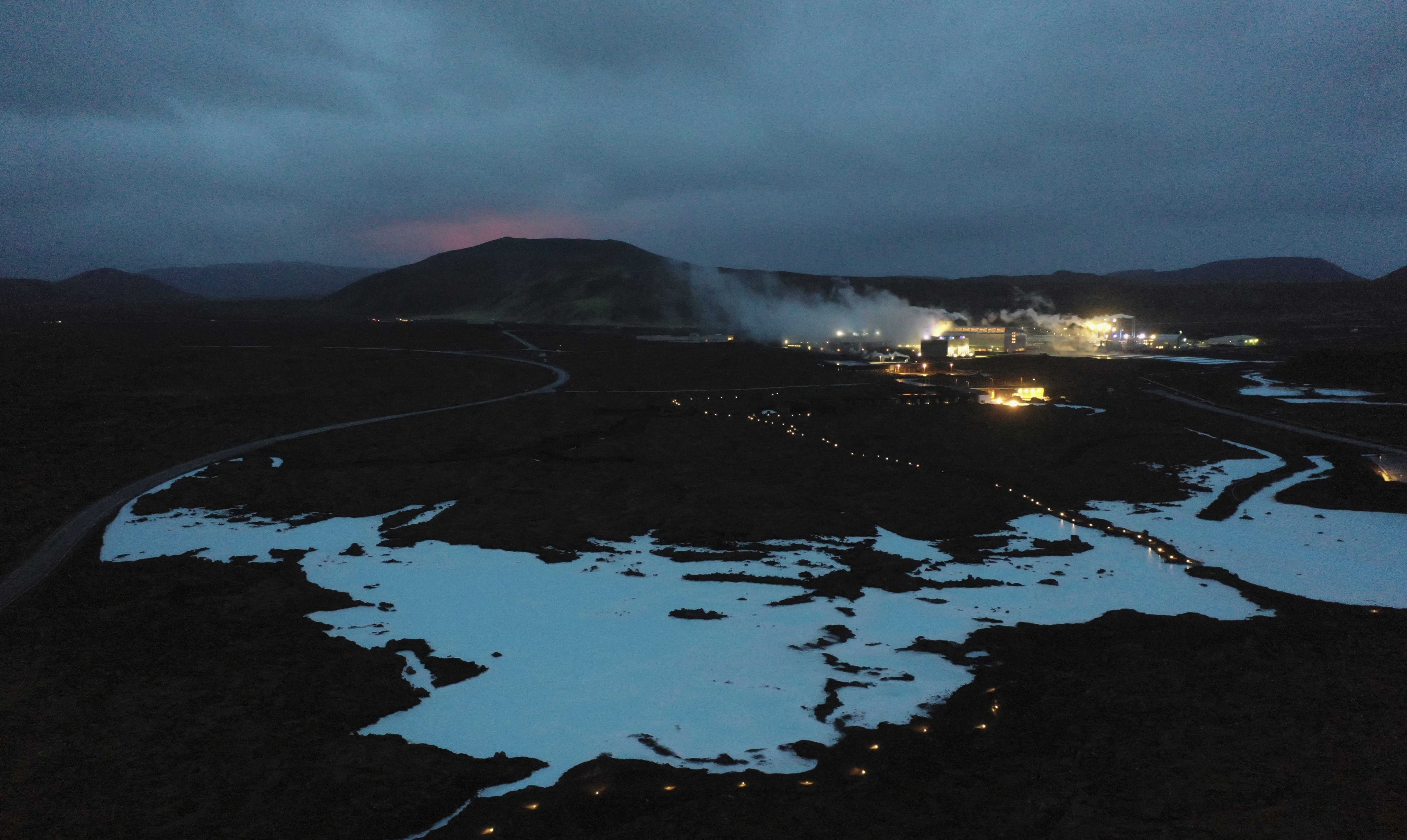 Imagen de archivo del brillo rojo del magma saliendo del volcán en erupción Fagradalsfjall detrás de la turística Laguna Azul, cerca de la ciudad de Grindavik, a unos 40 km al oeste de la capital islandesa, Reykjavik, el 20 de marzo de 2021.