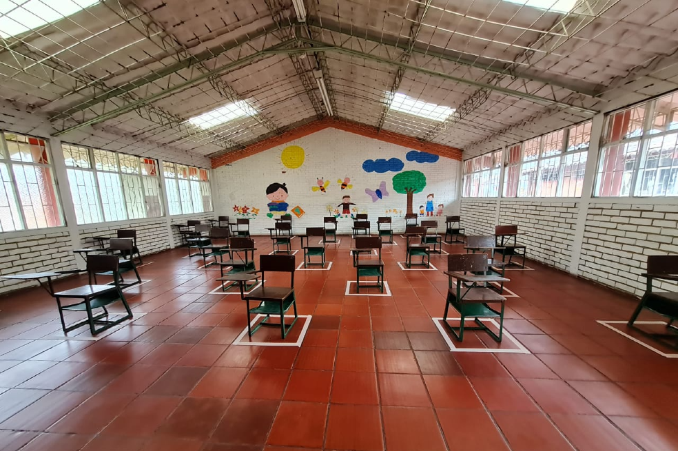 Un salón de clases con pupitres a cada dos metros.