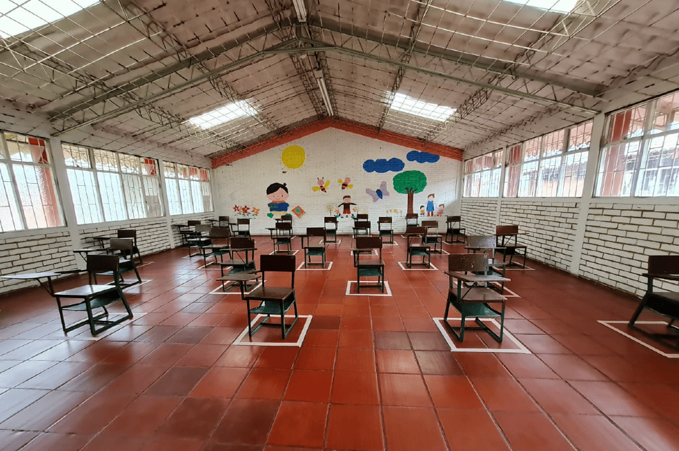 Un salón de clases con pupitres a cada dos metros.