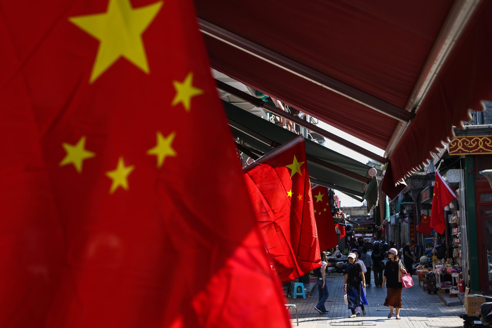 BEIJING (China), 01/09/2025.- People walk past Chinese national flags on a street in Beijing, China, 01 September 2025. A military parade on 03 September in Beijing will mark the 80th anniversary of the Victory Day of the Second Sino-Japanese War, known in China as the War of Resistance against the Japanese aggression, and the end of World War II. EFE/EPA/WU HAO