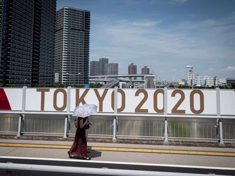 TOPSHOT - A woman walks along a street in downtown Tokyo on July 20, 2021, ahead of the Tokyo 2020 Olympic Games. / AFP / Loic VENANCE