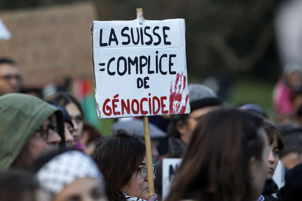Geneva (Switzerland), 16/12/2023.- A protester holds a placard reading 'Switzerland is complicit in genocide' during a rally in support of Palestinian people, in Geneva, Switzerland, 16 December 2023. Thousands of Israelis and Palestinians have died since the militant group Hamas launched an unprecedented attack on Israel from the Gaza Strip on 07 October, and the Israeli strikes on the Palestinian enclave which followed it. (Protestas, Suiza, Ginebra) EFE/EPA/SALVATORE DI NOLFI