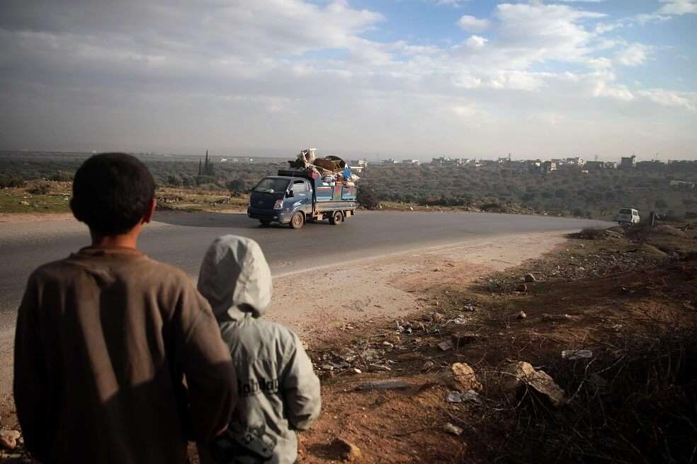 Dos niños observa un camión cargado de muebles y pertenencias, a unos siete kilómetros al sur de la ciudad de Idlib el 24 de diciembre de 2019. Los combates en los últimos cinco días han dejado más de 40.000 personas desplazadas.
