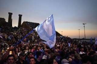 Supporters of Argentina's President Javier Milei wave an Argentine flag during the closing campaign rally of Libertad Avanza party ahead of the upcoming legislative elections in Rosario, Santa Fe province, Argentina on October 23, 2025.